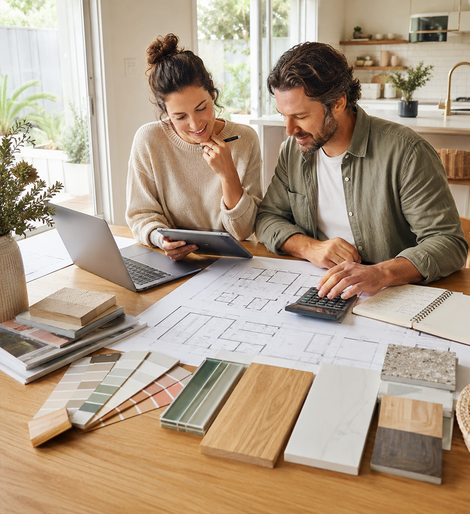 Couples are sitting at a wooden dining table reviewing architectural floor plans for a home